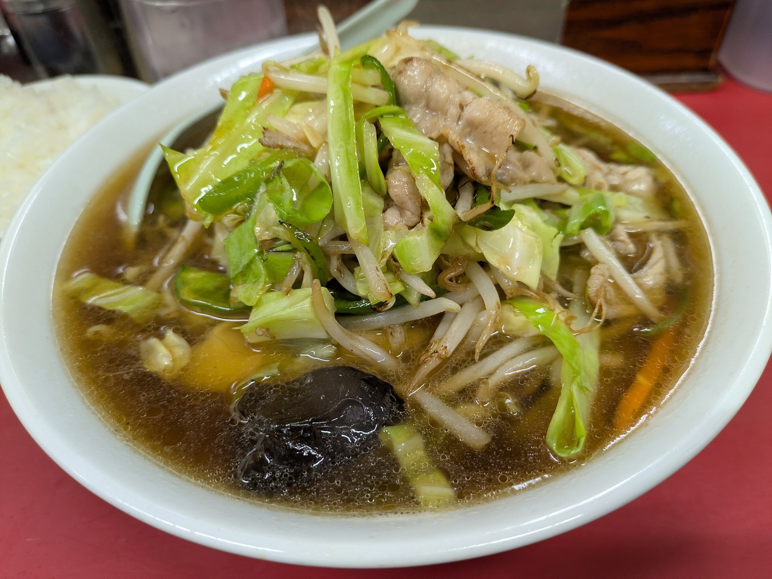 白い丸皿に盛られた野菜炒め風ラーメン、キャベツ・もやし・豚肉・きくらげが入った醤油スープ